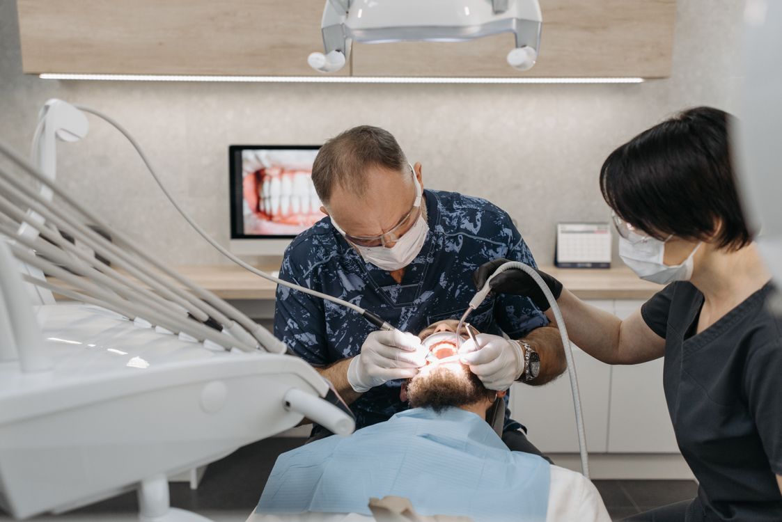 Dentist and hygienist treating a patient in a bright, modern dental clinic